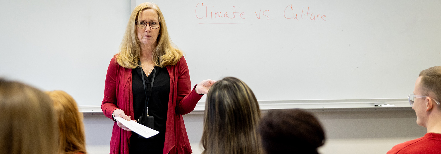 A woman stands in front of a classroom of students during a lecture.