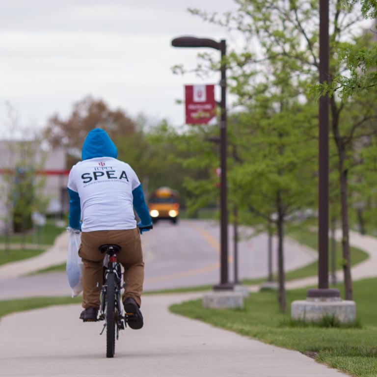 A SPEA student rides their bike on a city trail.