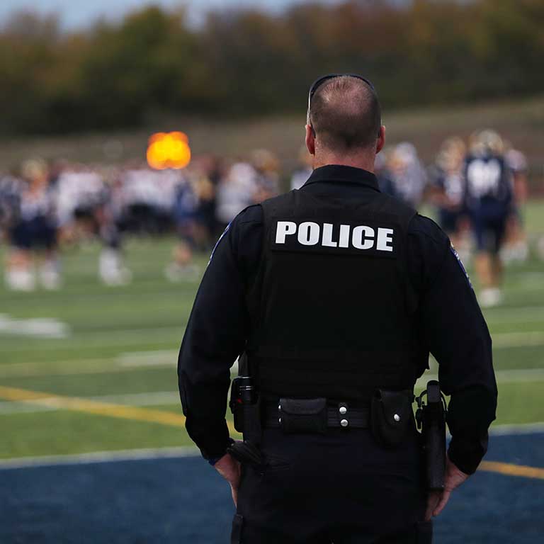 Stock photo of police officer at high school football game.