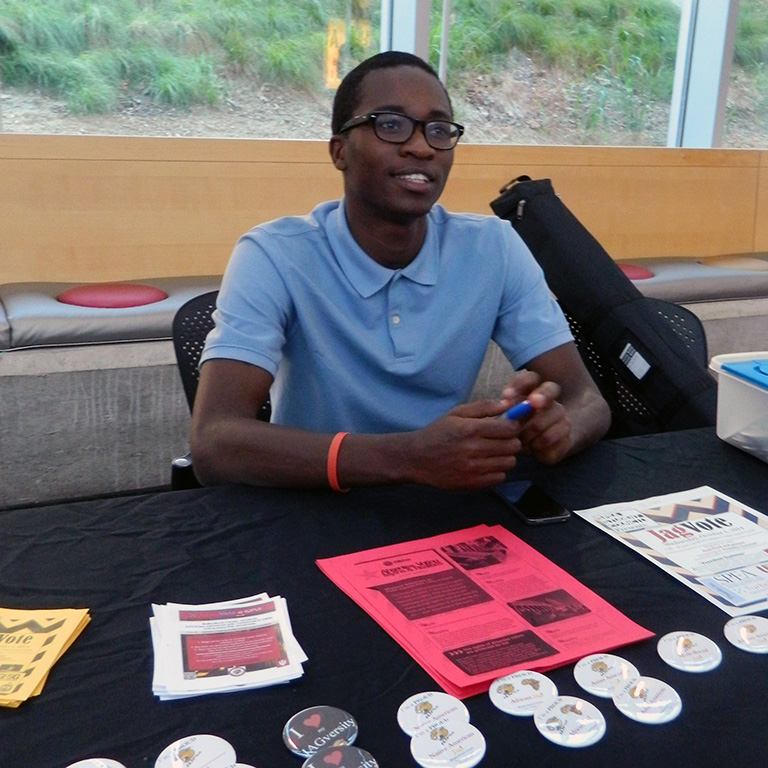 A SPEA student organization member passes out information at a booth. 